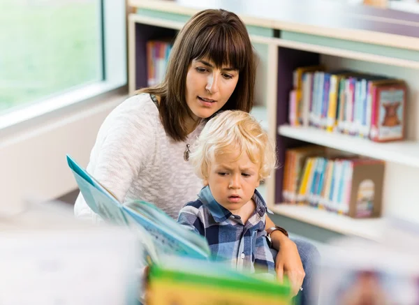 Schüler mit Lehrer lesen Buch in Bibliothek — Stockfoto