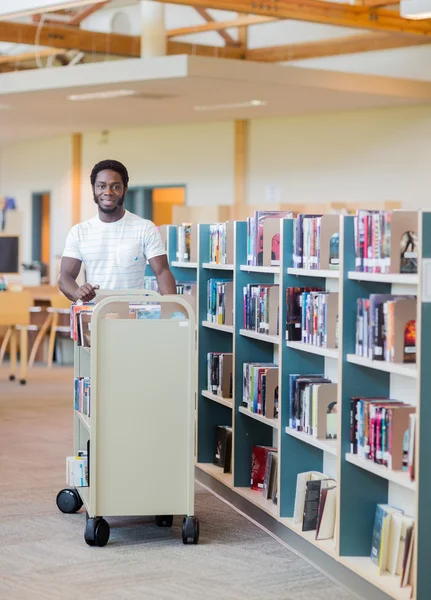 Bibliotekarie med vagnen av böcker i bokhandeln — Stockfoto