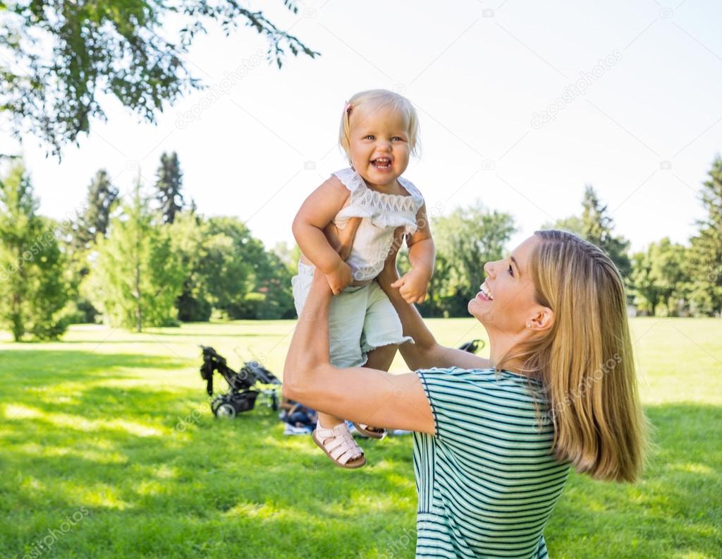 Mother Lifting Daughter In Park