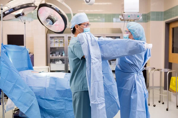 Peeling Krankenschwester legt sterilen Mantel auf Chirurgen — Stockfoto