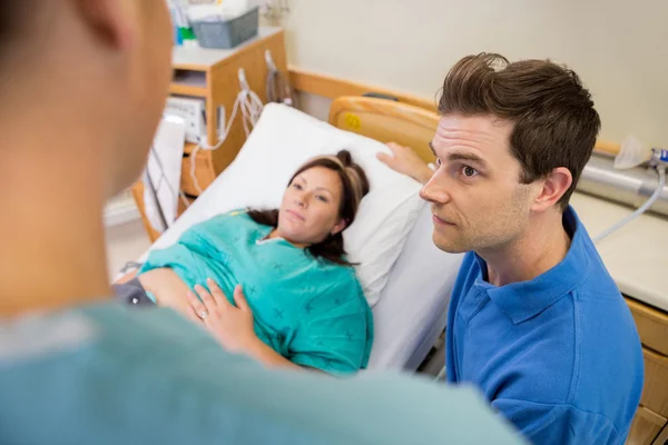 Man en zwangere vrouw luisteren naar verpleegkundige in het ziekenhuis — Stockfoto