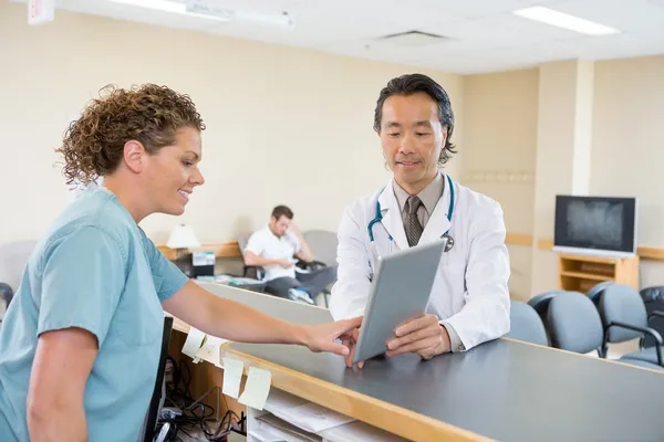 Lekarz i pielęgniarka za pomocą cyfrowego tabletu w recepcji szpitala — Zdjęcie stockowe