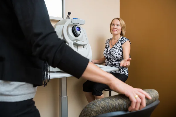 Optiker bittet Patient, im Geschäft zu sitzen — Stockfoto