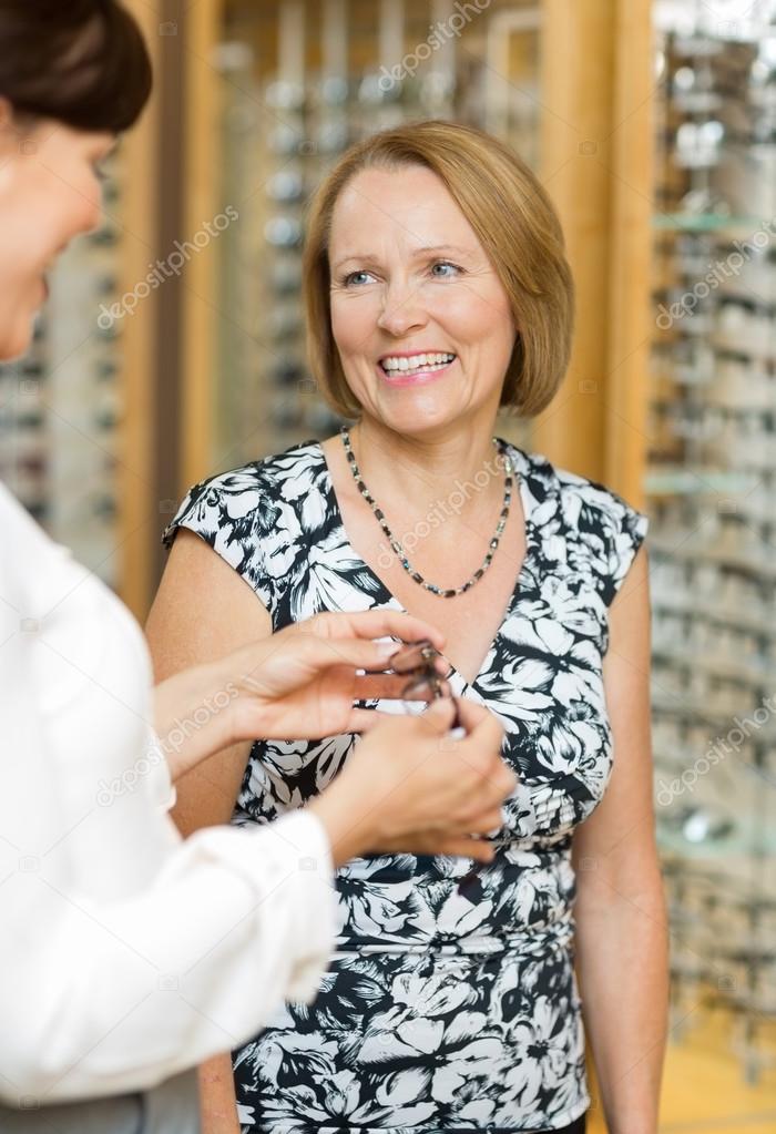 Salesgirl Assisting Senior Customer In Selecting Glasses