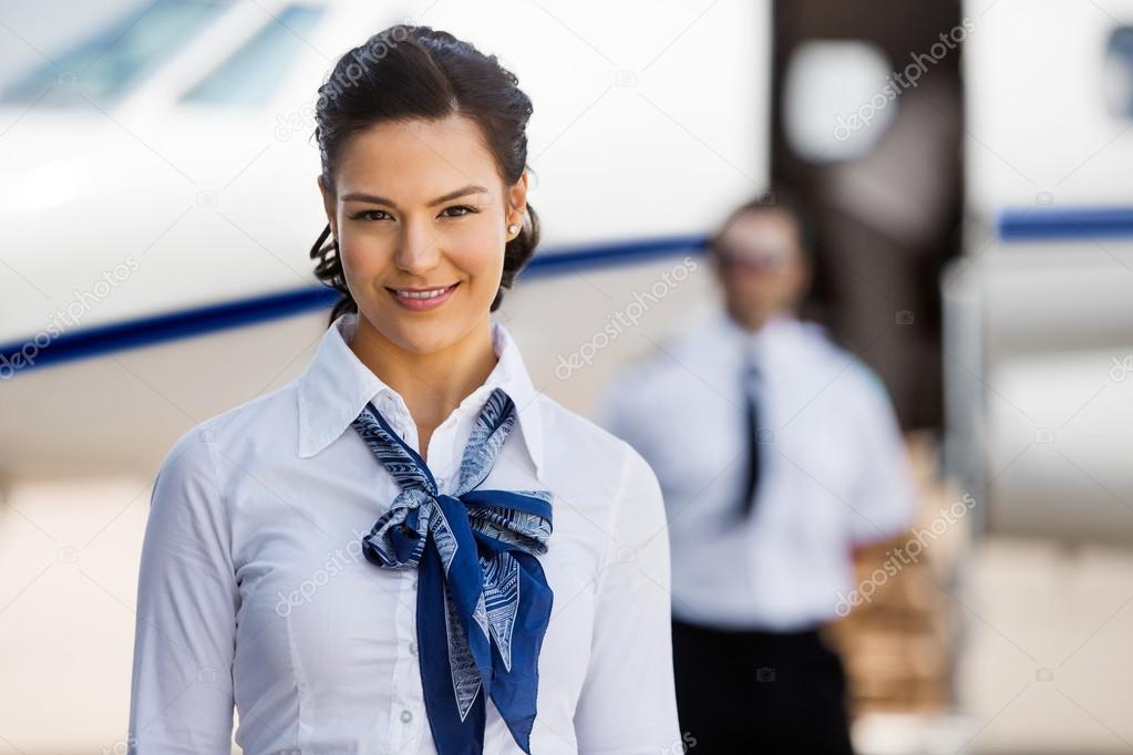 Pretty Stewardesses Smiling With Pilot And Private Jet In Backgr