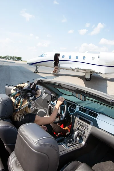 Frau im Cabrio mit Privatjet am Terminal — Stockfoto