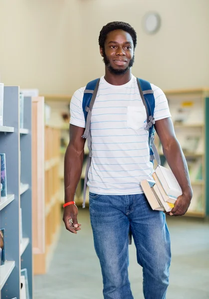 Student med böcker som tittar bort i biblioteket — Stockfoto