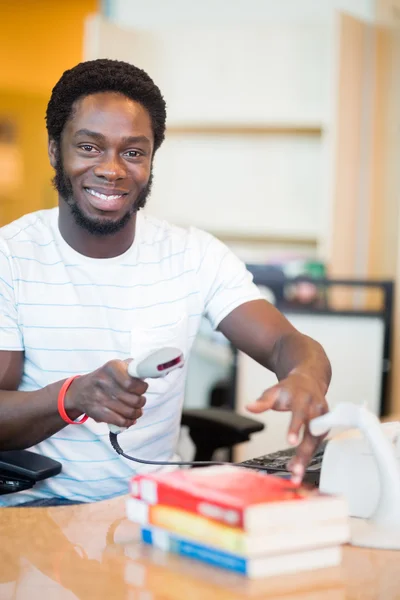 Smiling Librarian Scanning Books at Library Desk — стоковое фото