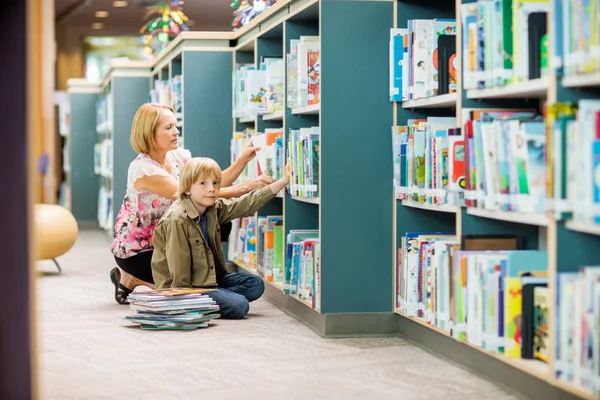 Boy With Teacher Selecting Books From Bookshelf — Stock Photo, Image