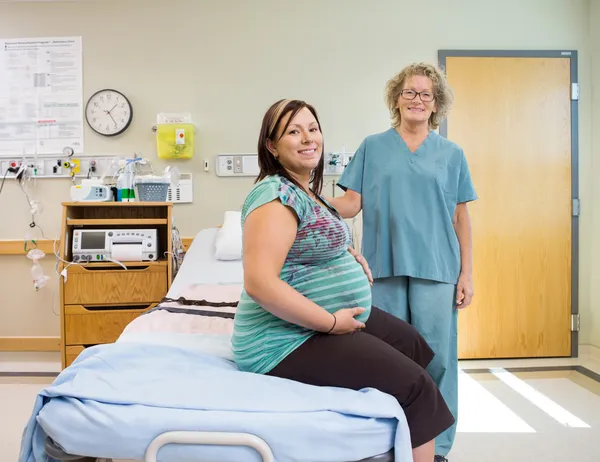 Glad sjuksköterska och gravid kvinna i sjukhusrummet — Stockfoto