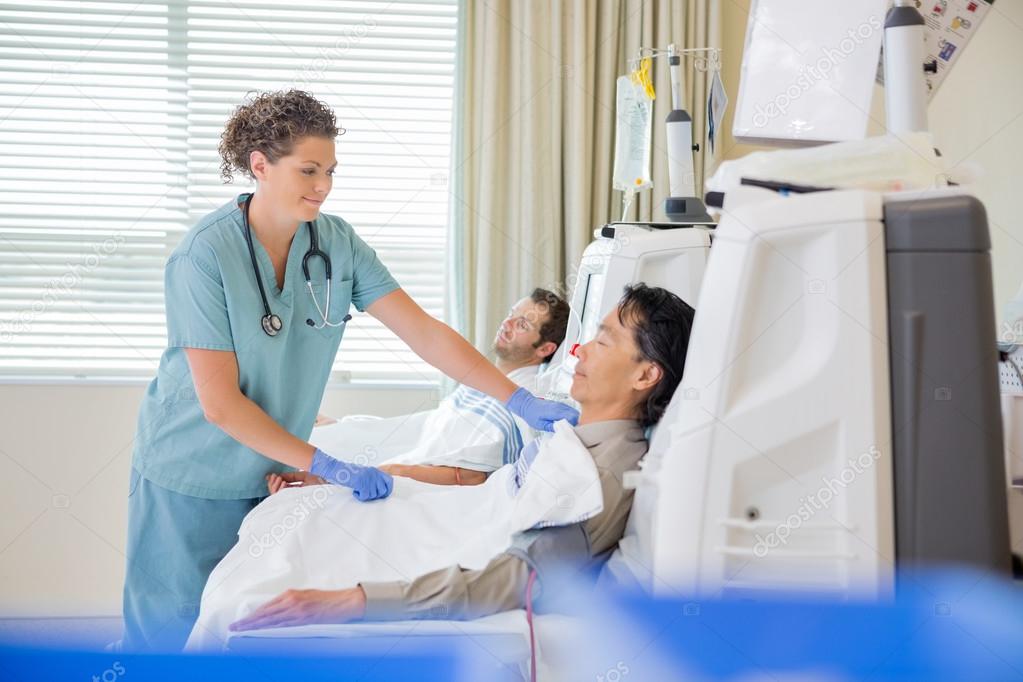 Nurse Assisting Patient Undergoing Renal Dialysis Stock Photo by
