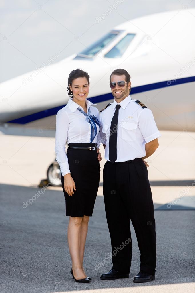 Airhostess And Pilot Standing Against Private Jet