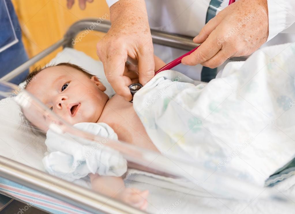 Doctor's Hands Examining Newborn Babygirl In Hospital