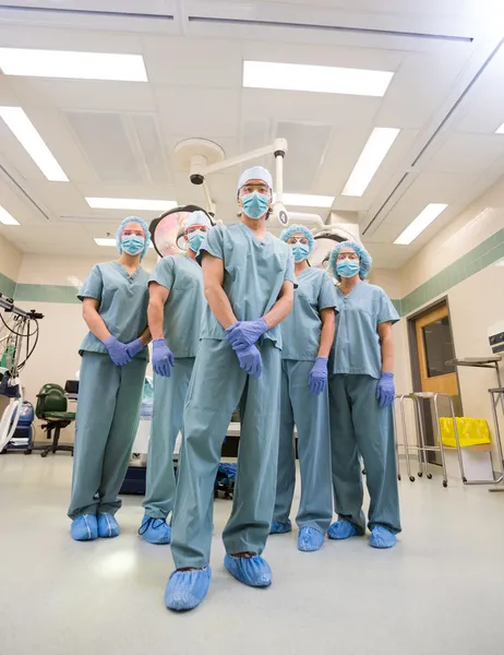 Squadra medica in strofinacci in piedi all'interno della sala operatoria — Foto Stock