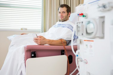 Patient Holding Mobilephone at Renal Dialysis Center clipart