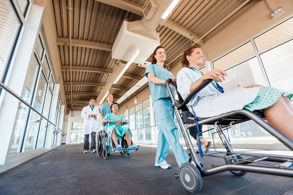 Enfermeras empujando a pacientes en sillas de ruedas con médico en el corredor — Foto de Stock