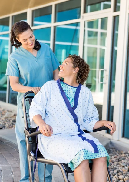 Patiënt kijken vriendelijke verpleegster zittend op rolstoel — Stockfoto