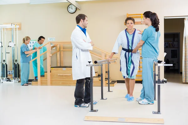 Fisioterapeutas que ayudan a la paciente femenina a caminar — Foto de Stock