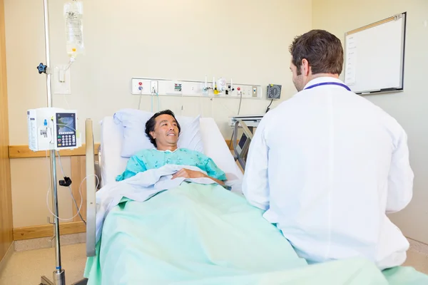 Paciente maduro mirando al médico mientras está acostado en la cama del hospital — Foto de Stock