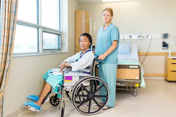 Patient im Rollstuhl, während Krankenschwester am Fenster steht — Stockfoto