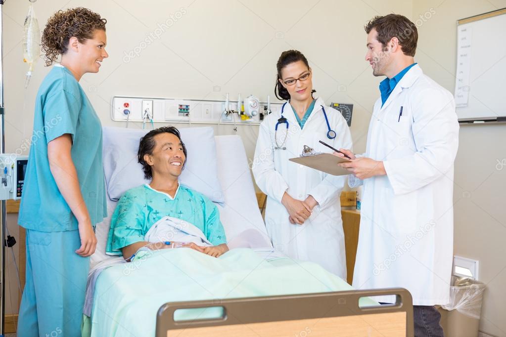 Doctors Discussing Notes While Patient And Nurse Looking At Them