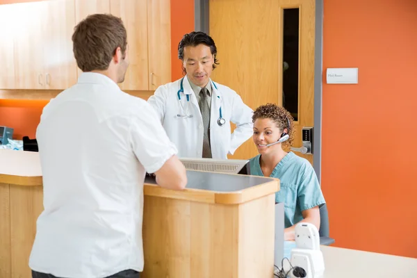 Doctor And Nurse Working While Man Standing In Hospital — Stock Photo, Image