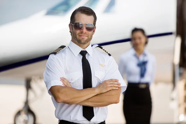 Pilot With Arms Crossed Standing Against Stewardess And Private — Stock Photo, Image