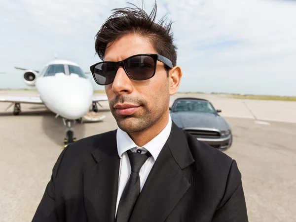 Fiducioso uomo d'affari di fronte a auto e jet privato — Foto Stock