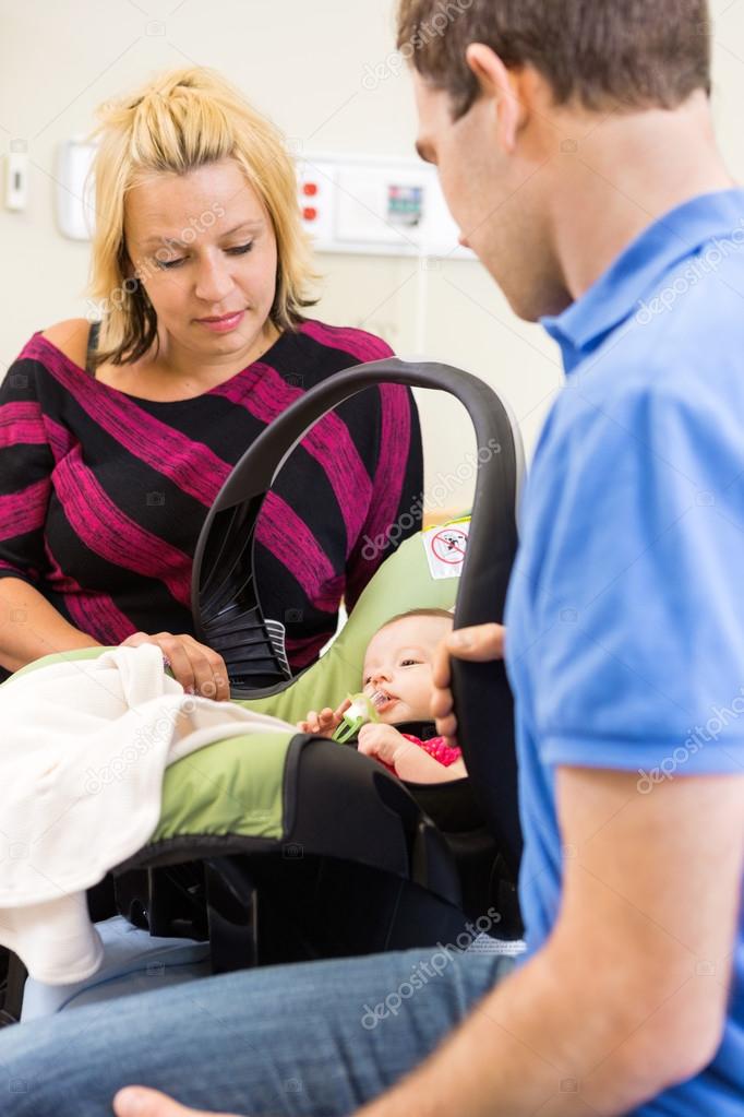 Couple Looking At Newborn Baby In Carrier At Hospital