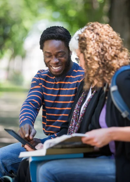 Glad student med digital tablet med vänner på campus — Stockfoto