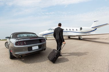Businessman Standing By Car And Private Jet At Terminal