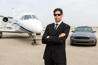 Araba ve özel jet önünde duran işadamı