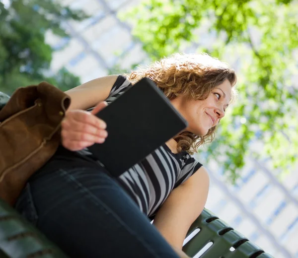 Estudiante universitario sosteniendo tableta digital en el banco — Foto de Stock