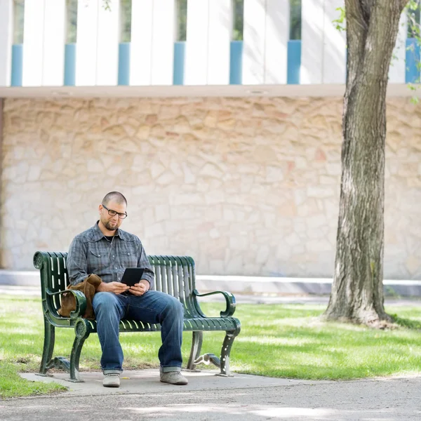 Φοιτητή πανεπιστημίου που χρησιμοποιεί ψηφιακή δισκίο σε παγκάκι — Φωτογραφία Αρχείου