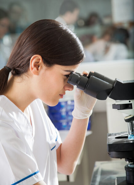 Female Researcher Looking Into Microscope In Lab