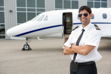 Smiling Pilot Standing In Front Of Private Jet clipart