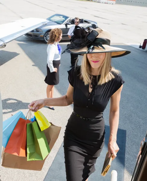 Gazdag nő, könyv bevásárló táskák, miközben bentlakásos privát jet — Stock Fotó