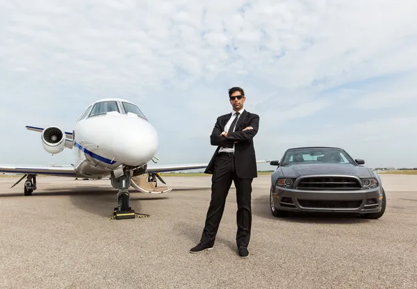 Biznesmen stojący samochód i prywatny odrzutowiec w terminalu — Zdjęcie stockowe
