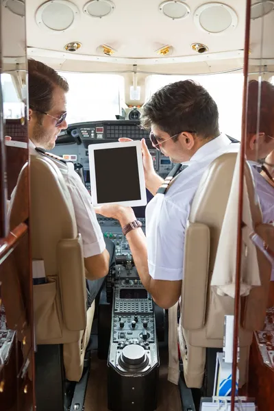 Pilot visar digitala tablett till copilot i cockpit — Stockfoto