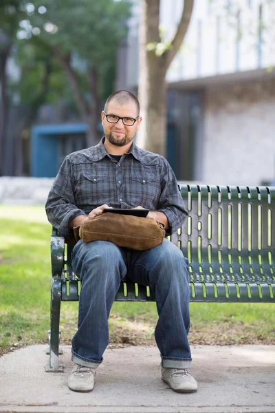 Lächelnder männlicher Student sitzt auf Bank — Stockfoto