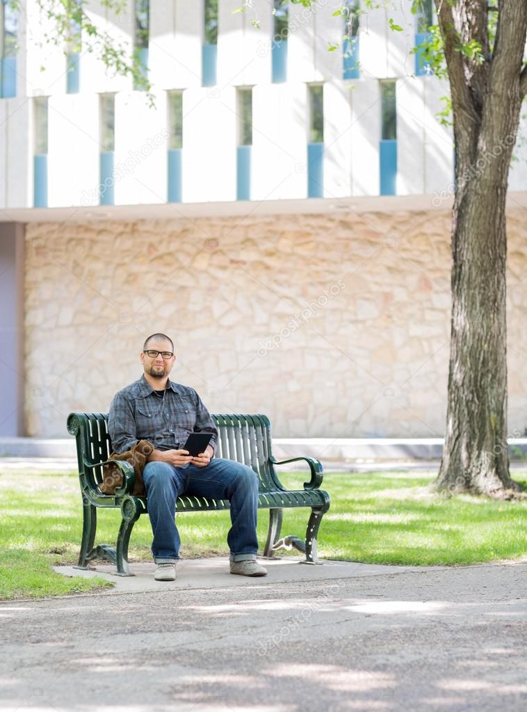Student Sitting On Bench At University Campus