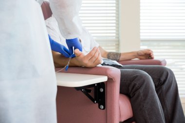 Nurse Adjusting IV Drip On Patient's Hand In Chemo Room clipart