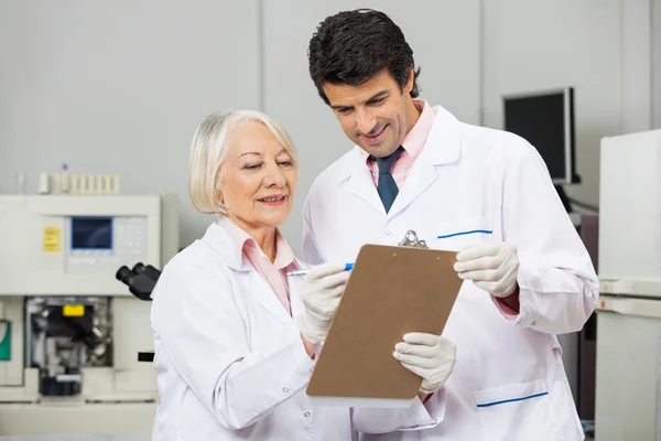 Técnicos escribiendo en portapapeles en laboratorio — Foto de Stock