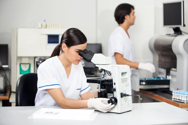 Cientista feminina usando microscópio em laboratório — Fotografia de Stock