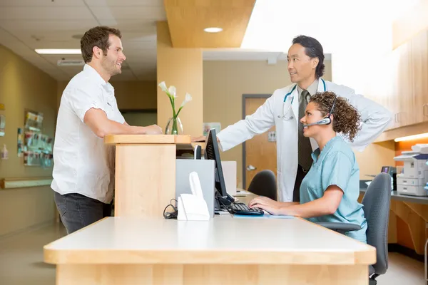 Paciente com médico e enfermeira na recepção — Fotografia de Stock