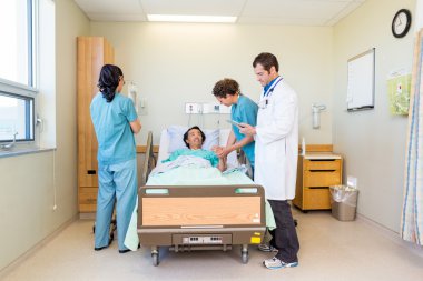 Nurses And Doctor Examining Patient In Hospital clipart