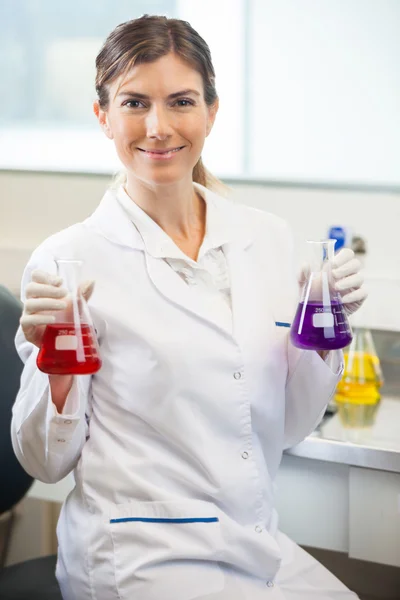 Cientista examinando frascos com produtos químicos diferentes — Fotografia de Stock