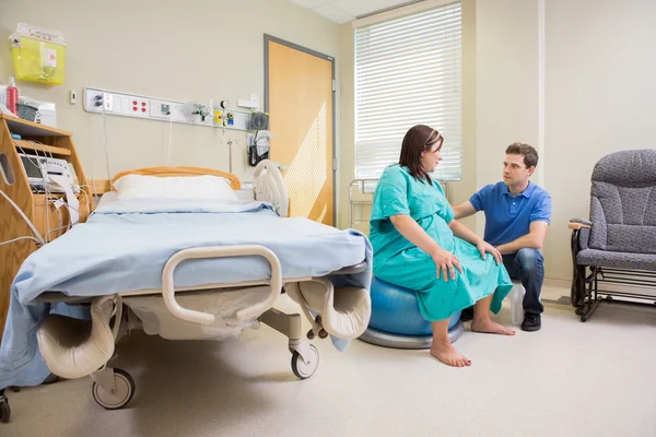 Man kijken zwangere vrouw op oefening bal in het ziekenhuis — Stockfoto