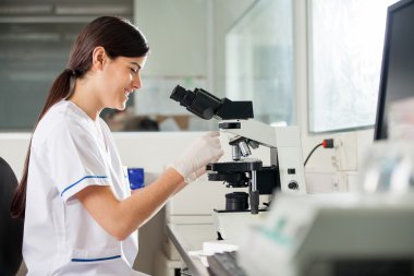 Laboratuarda mikroskop kullanarak mutlu kadın bilimci