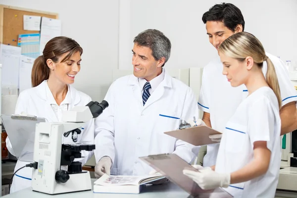 Investigador con estudiantes tomando notas en el laboratorio — Foto de Stock